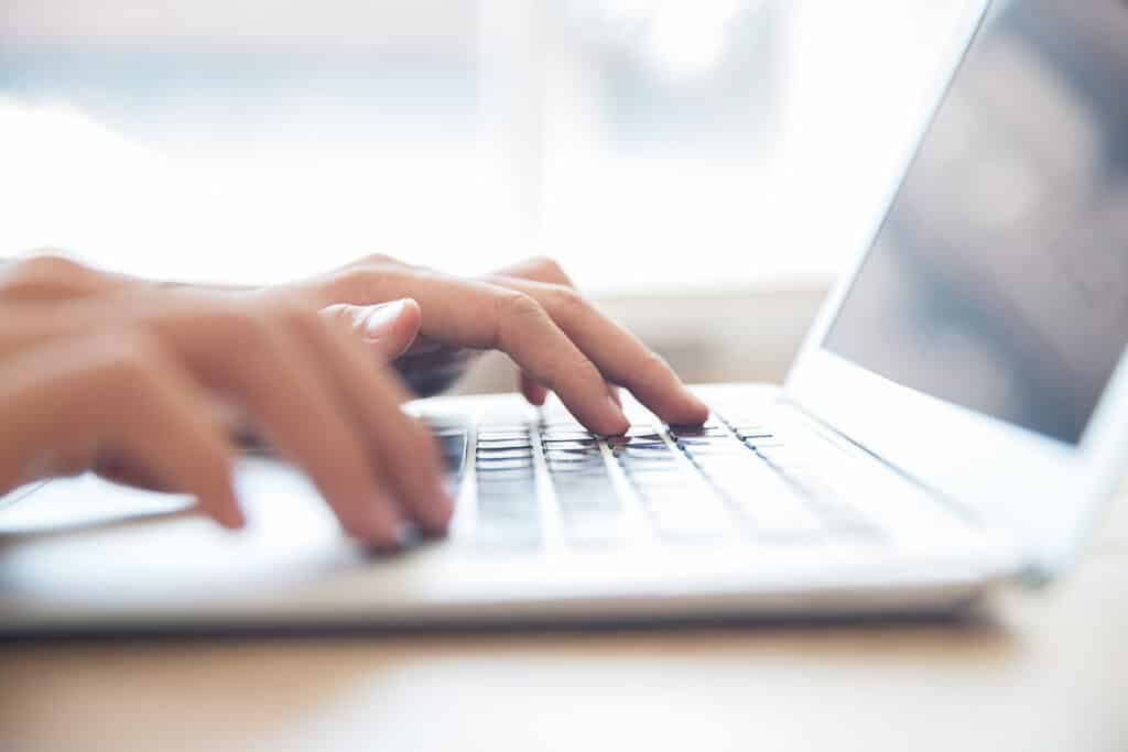 Mains tapant sur le clavier d’un ordinateur portable